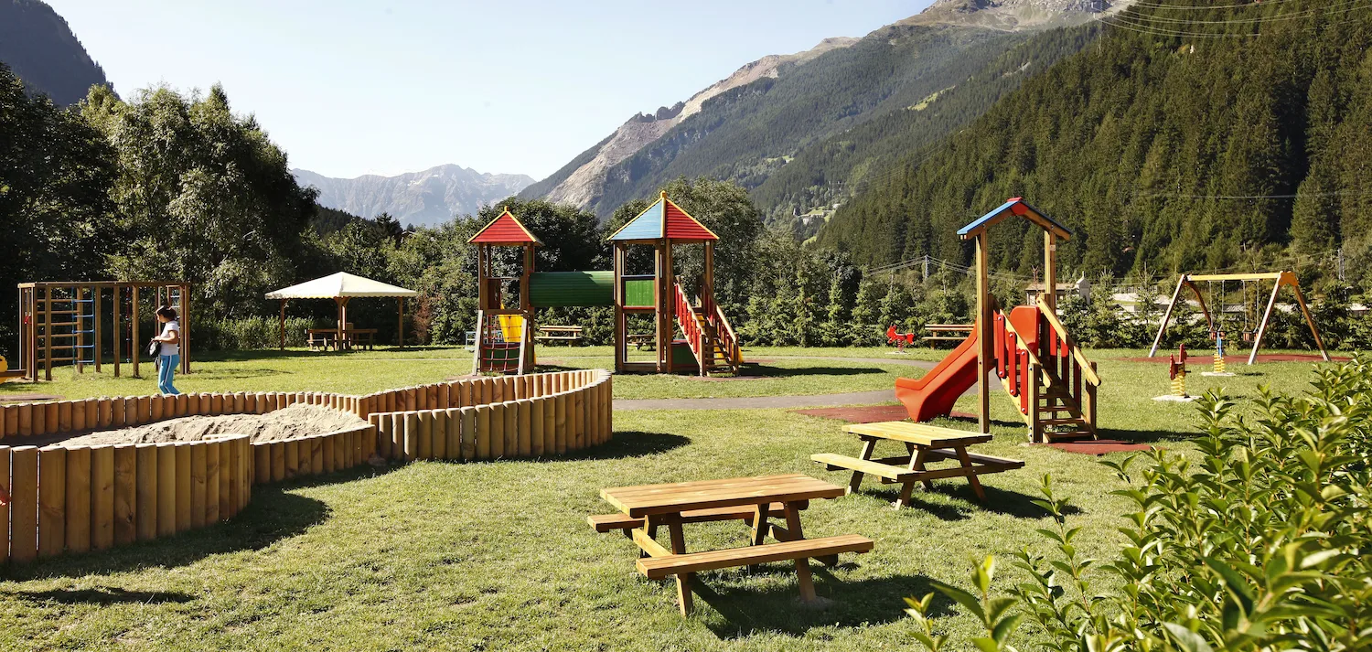 Parco giochi in area montana con giochi in legno e tavoli da esterno per bambini